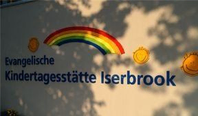 Schild "Evangelische Kindertagesstätte Iserbrook" mit Regenbogen.